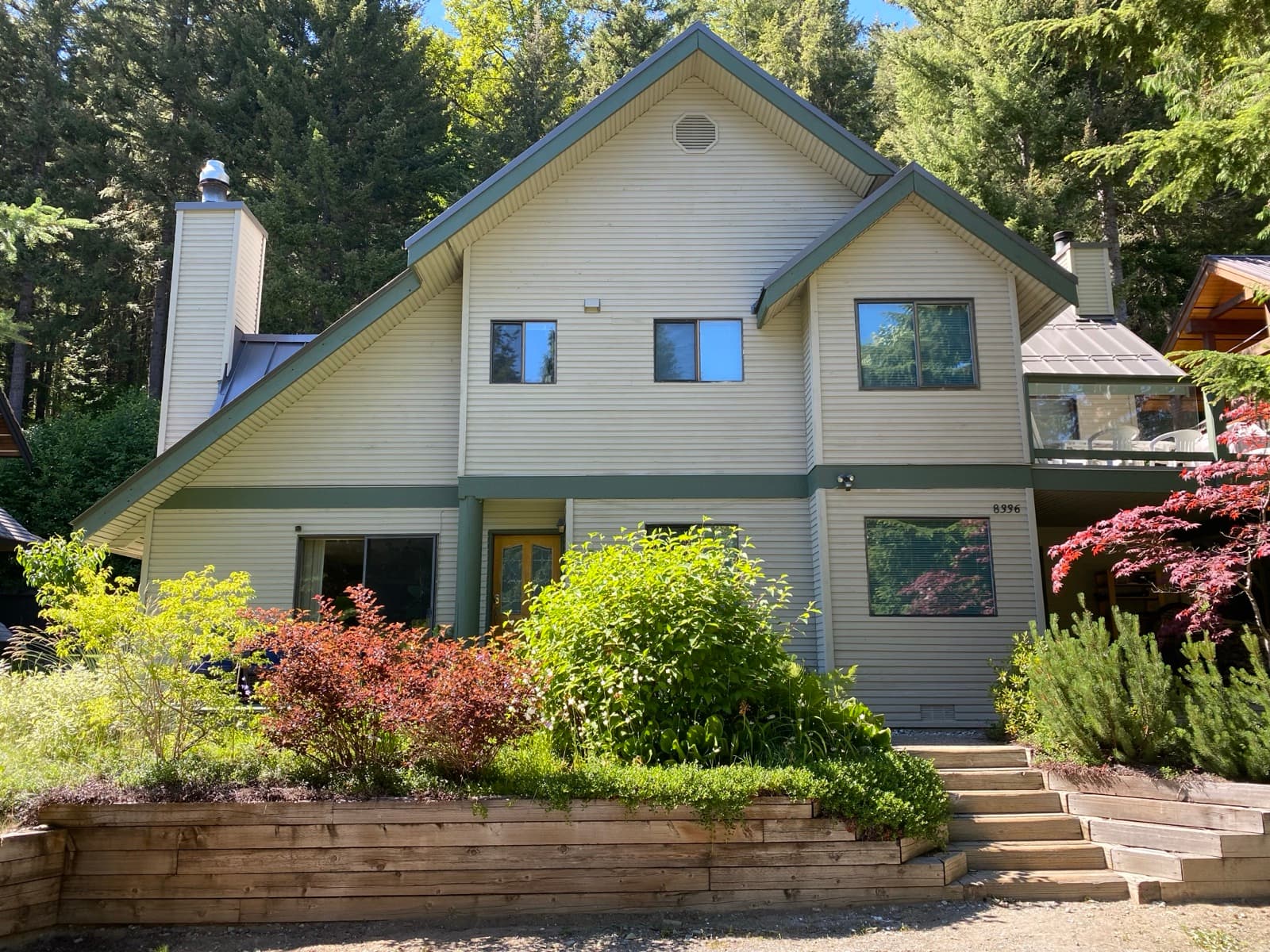 Front elevation of a two-storey house with cream lap siding, sage-green trim bands and gables
