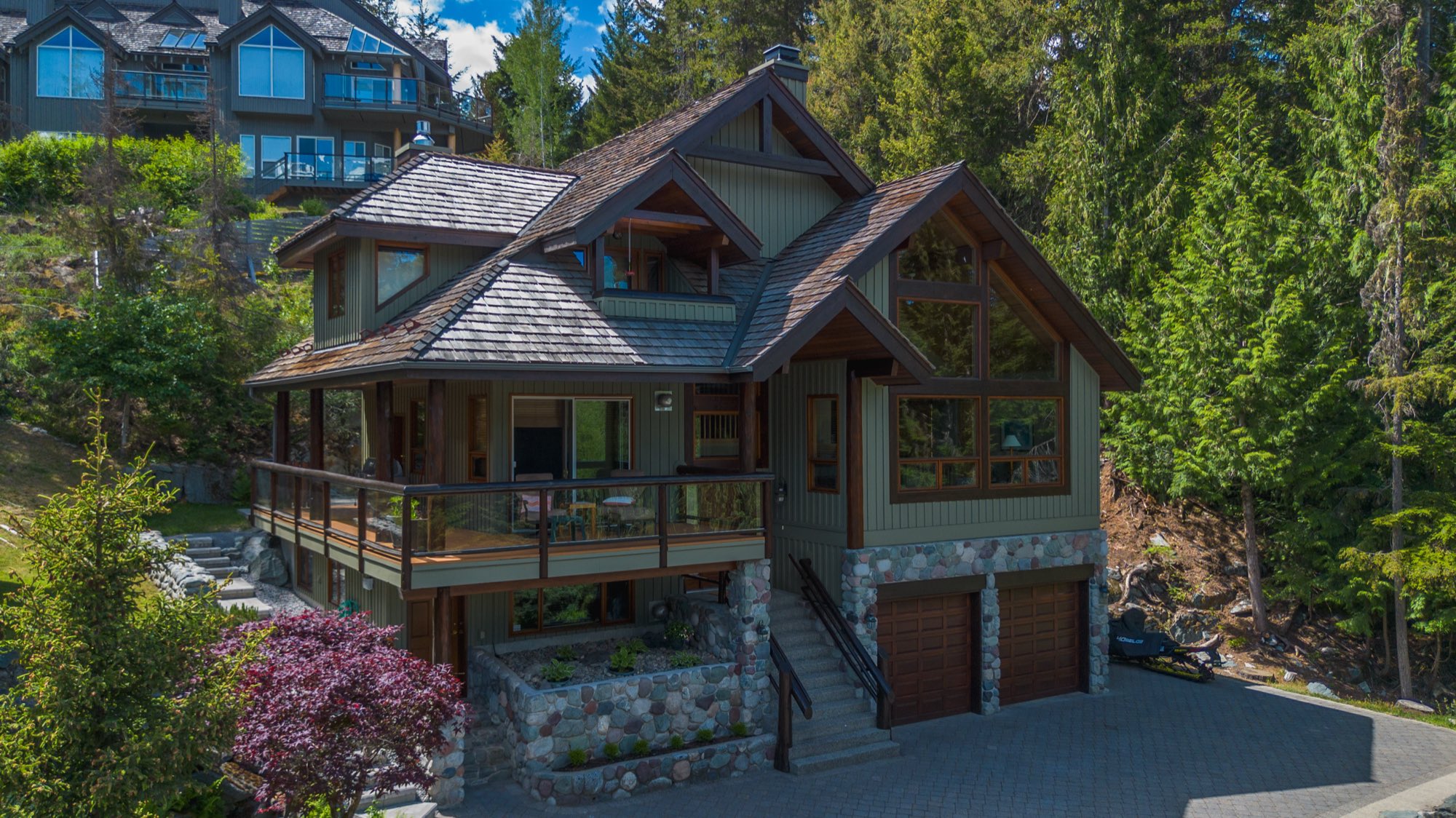 Green-stained timber-frame chalet with cedar accents and stone base — Whistler, BC